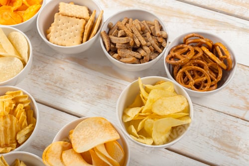 Preview: Snack bowls filled with various crunchy foods on a wooden table during a gathering