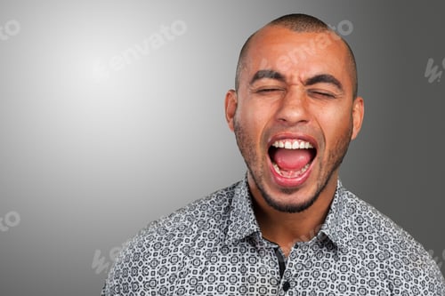 Preview: Man yells loudly in a studio with gray background while wearing a patterned shirt