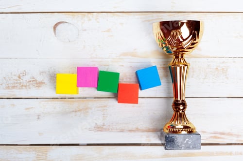 Preview: Trophy and colorful blocks on wooden surface during bright indoor setting