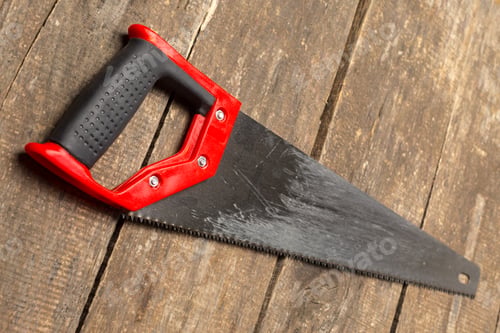 Preview: Tool placed on a wooden surface showing a red and black hand saw ready for use during a project
