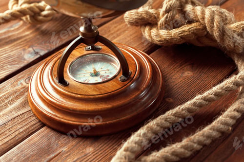 Preview: Compass on wooden table with rope nearby in a nautical setting during daylight hours