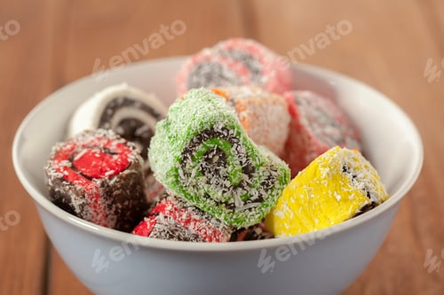 Preview: Fruit candy rolls in a bowl on a wooden table during the daytime
