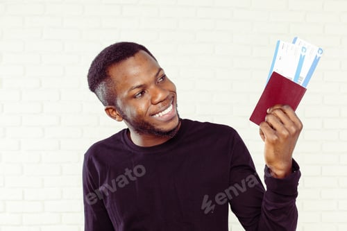 Preview: Man smiles and holds passport with tickets in a bright setting