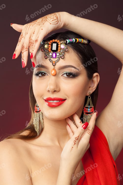 Preview: Model poses with jewelry and henna on skin at studio with a dark background