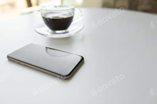 Preview: Coffee sits on a table next to a smartphone during morning hours at a café