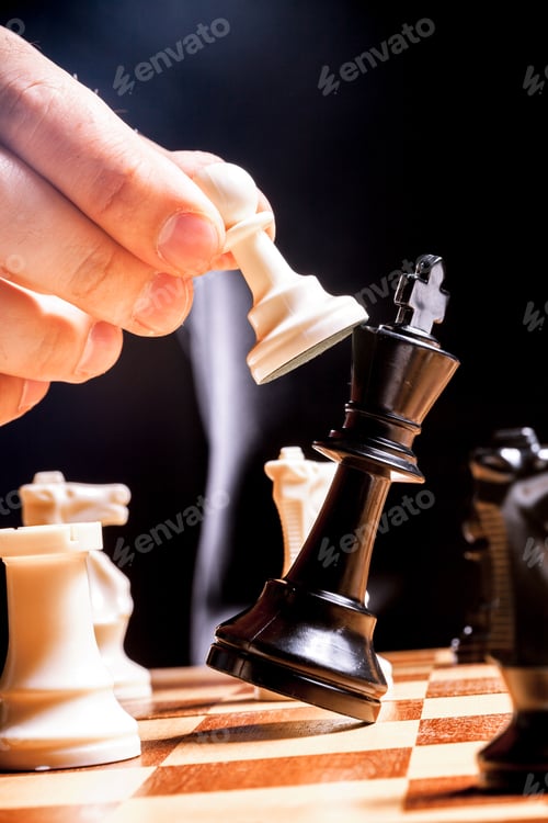 Preview: Chess player moves a piece during a match in a dark setting in 2023