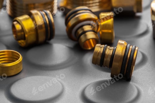 Preview: Brass fittings and connectors arranged on a black surface in a workshop setting