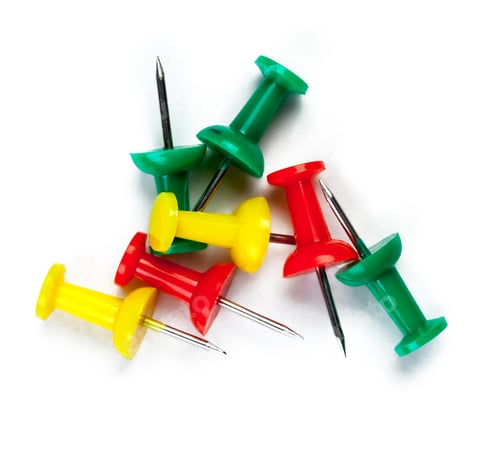 Preview: Colored push pins are scattered on a white background in a creative workspace