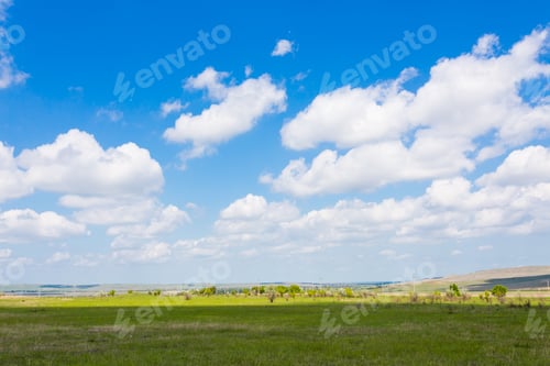 Preview: Clear sky over green fields with fluffy clouds during midday in a rural setting