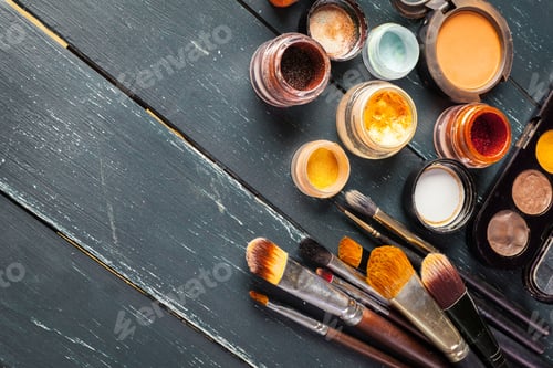 Preview: Different kinds of makeup products and brushes on a wooden table with natural light