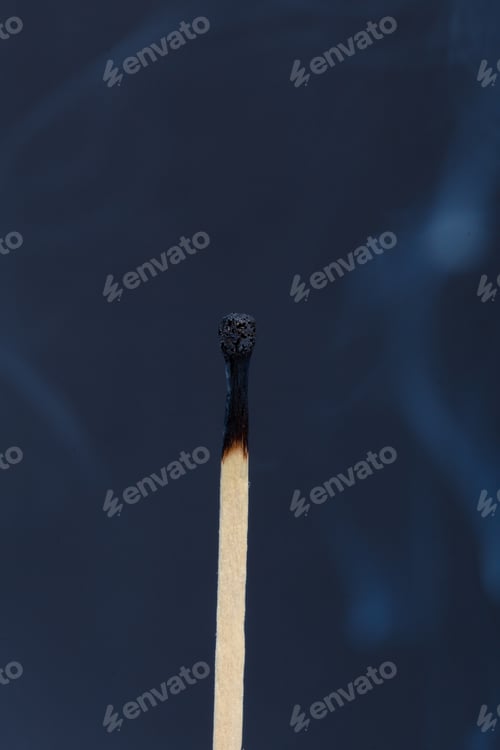 Preview: Close-up of a matchstick standing upright with smoke in the background during nighttime