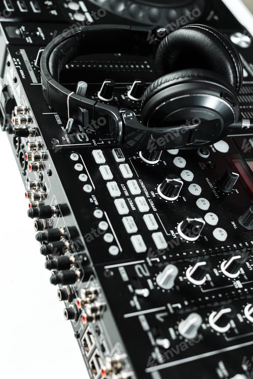 Preview: Headphones placed on a DJ mixer during a music session in a studio at night