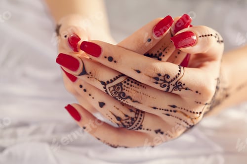 Preview: Woman with red nails shows henna designs on hands for body art display in bright light