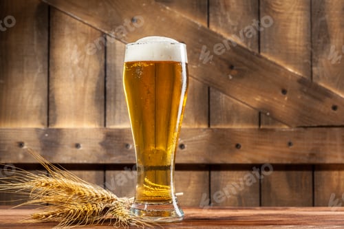 Preview: Craft beer in a glass on a wooden table with wheat beside it in a rustic setting