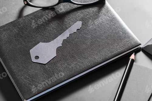 Preview: Key placed on black notebook with pencil and glasses on table at workspace during daytime