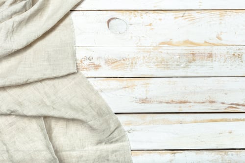 Preview: Natural linen cloth drapes over a wooden surface in a simple setting during daylight hours