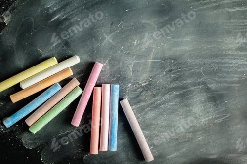 Preview: Colorful chalk pieces on a blackboard ready for drawing or writing in a classroom setting