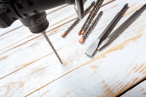 Preview: Power drill and tools arranged on a wooden surface in a workspace setting