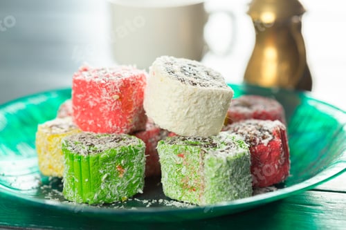 Preview: Colorful candy on a green plate with a cup in the background in a kitchen setting