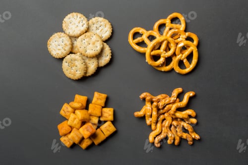 Preview: Snack assortment with crackers, pretzels, cheese puffs, and cheese cubes on black background