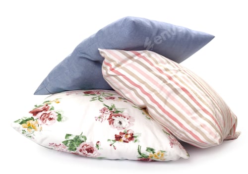 Preview: Soft pillows stacked in different patterns on a plain background in a bright space