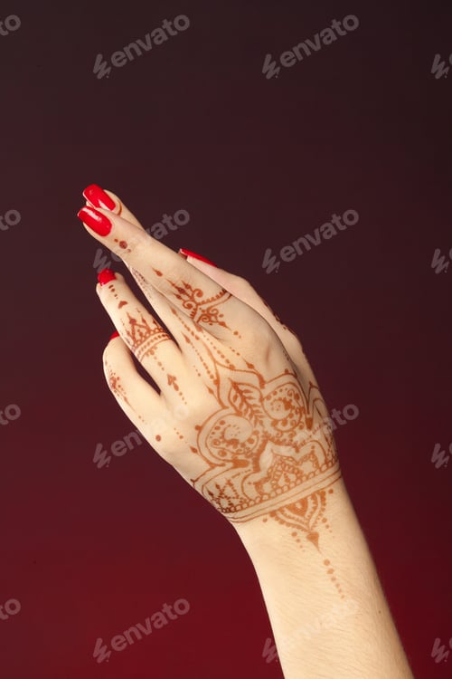 Preview: Henna design on hand with red nails in close view during celebration event in evening light