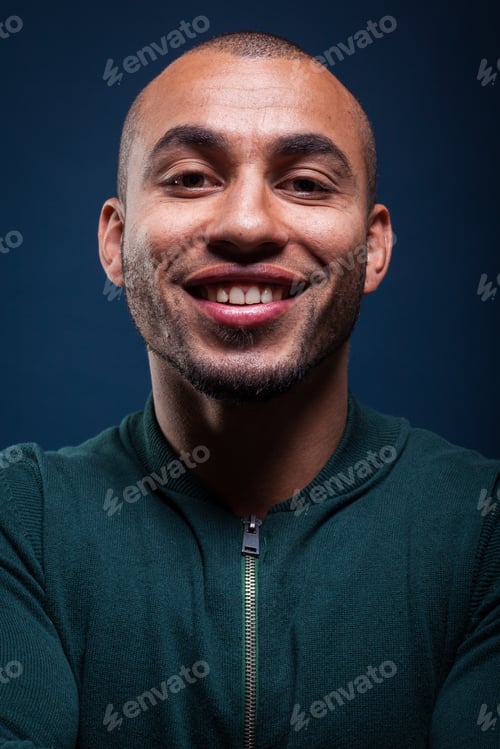 Preview: Smiling man with short hair and a green sweater against a dark blue background