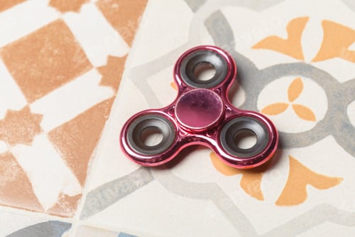 Preview: Fidget spinner rests on colorful tiled surface in a relaxed setting
