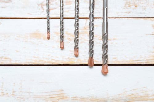 Preview: Different sizes of drill bits arranged on a wooden surface in a workshop setting