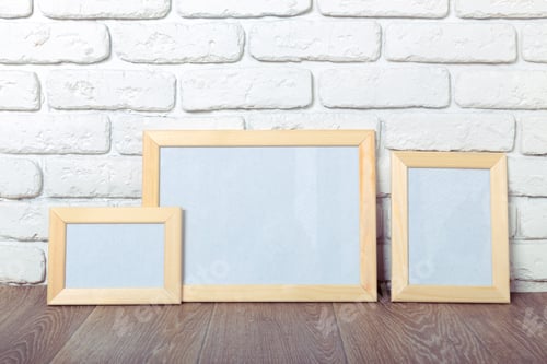 Preview: Frames are arranged on a wooden floor against a brick wall in a bright room