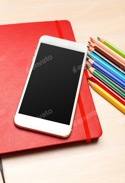 Preview: Study tools are arranged on a wooden table with a notebook, phone, and colored pencils