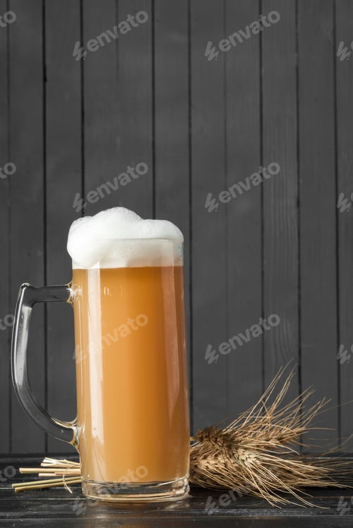 Preview: Craft beer served in a glass next to barley on a dark wooden surface