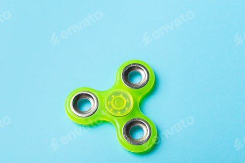 Preview: Bright green fidget spinner rests on a blue background during a casual play session
