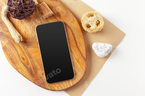 Preview: Smartphone on wooden board with natural items and stones during afternoon light