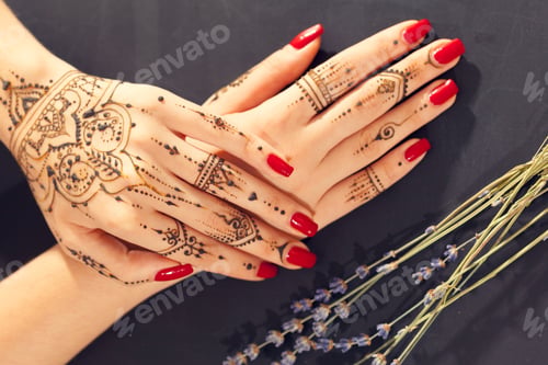 Preview: Henna design on hands with red nail polish and lavender on dark background