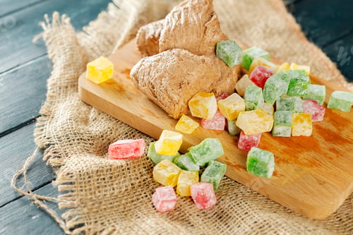 Preview: Colorful candies and ginger pieces on a wooden board on a burlap cloth