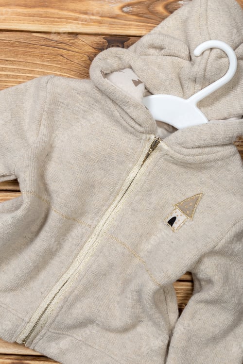 Preview: Soft gray hoodie with house design on wooden background in a cozy setting