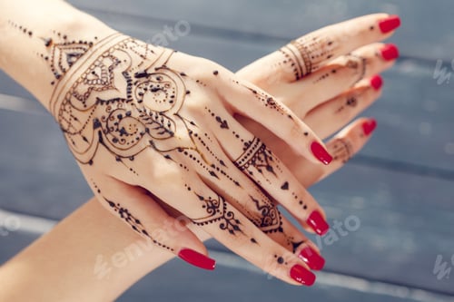 Preview: Henna design on hands with bright red nails at a celebration event in a simple setting