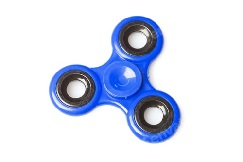 Preview: Bright blue fidget spinner sits on plain white surface during bright indoor light
