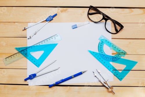 Preview: Tools for drawing and measuring on a wooden table with a blank sheet of paper in view