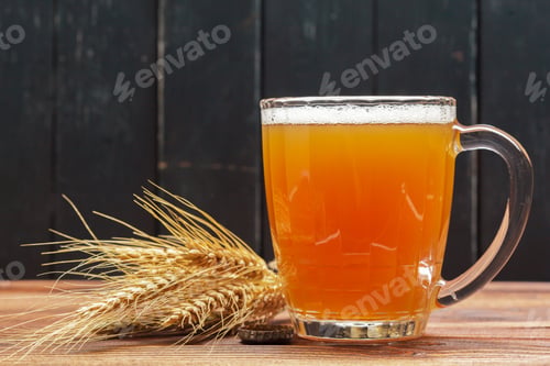 Preview: Clear glass mug of beer placed on wooden table near wheat stalks in a dim area