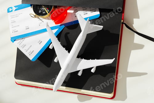 Preview: Planning a trip with travel tickets, a model plane, and a compass on a travel journal