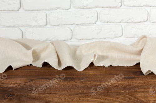 Preview: Woven fabric drapes over wooden surface near white brick wall during indoor setting