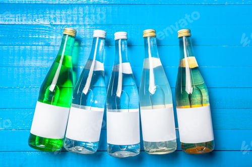 Preview: Bottles of water arranged on a blue wooden table during daytime