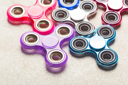 Preview: Colorful fidget spinners are placed together on a flat surface in natural light
