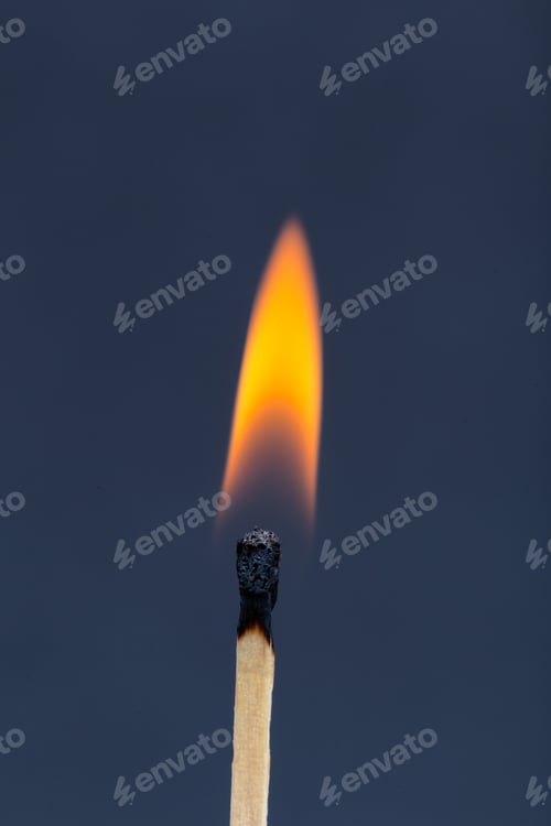 Preview: Flame from a matchstick burns brightly against a dark background at night