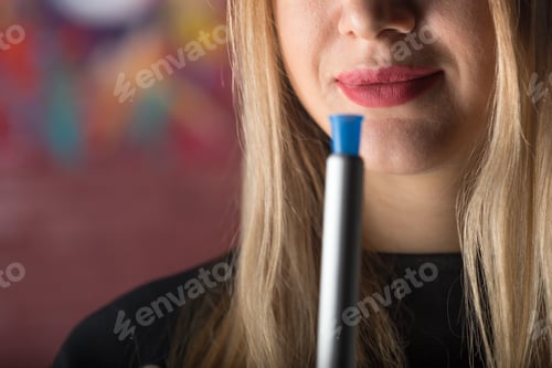 Preview: Woman with blue marker stands in front of colorful wall while posing for the camera