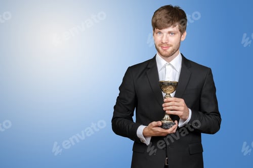 Preview: Person holds trophy while wearing a suit against a blue background at an award event