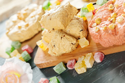 Preview: Different sweet treats on a wooden board with colorful candies around