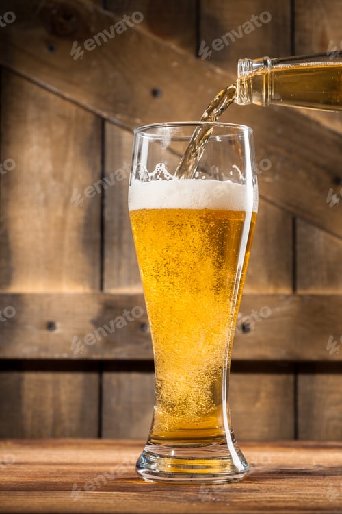 Preview: Pouring beer into a tall glass on a wooden table at a bar